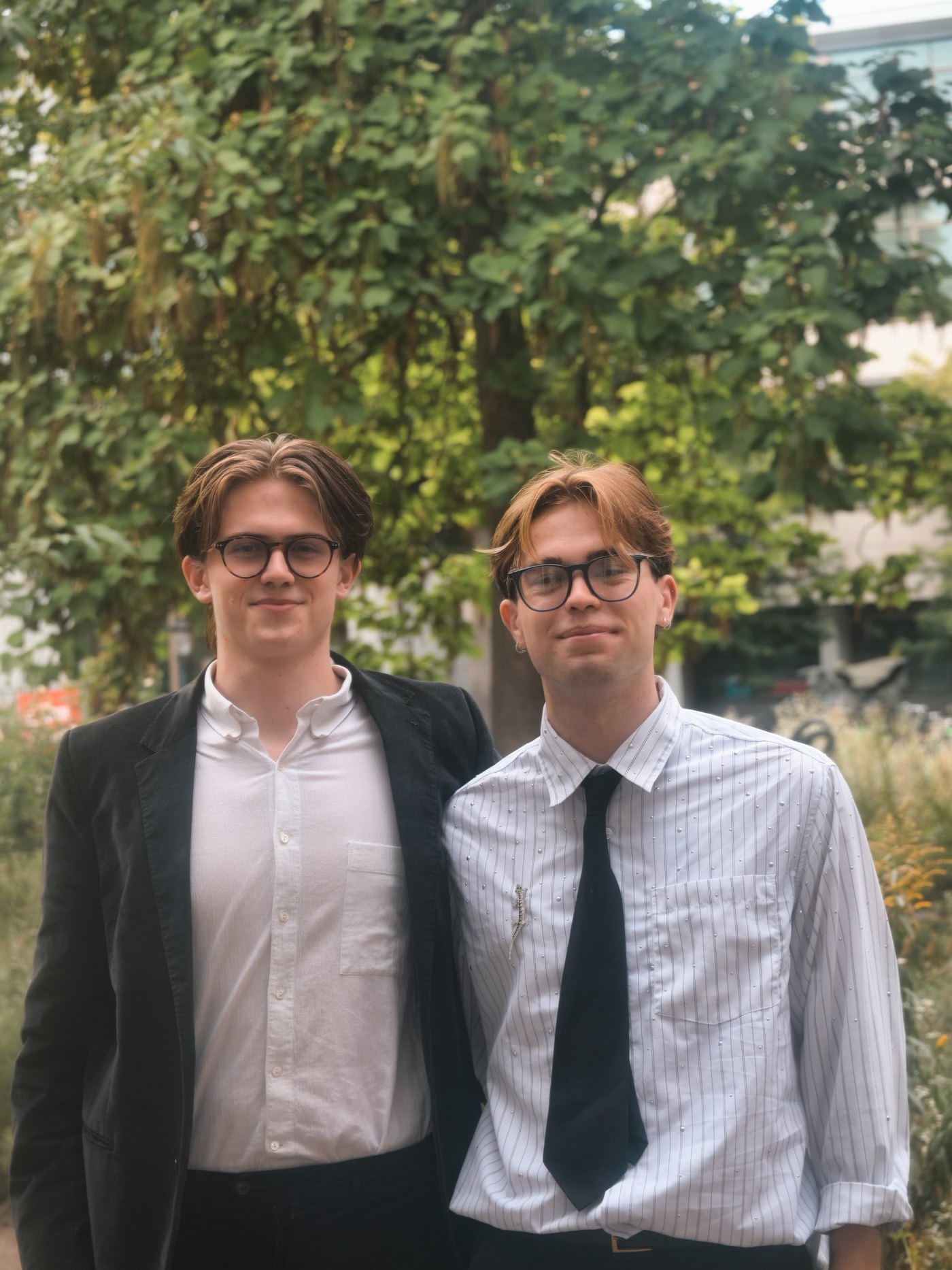 Two members in suits and ties outdoors among trees